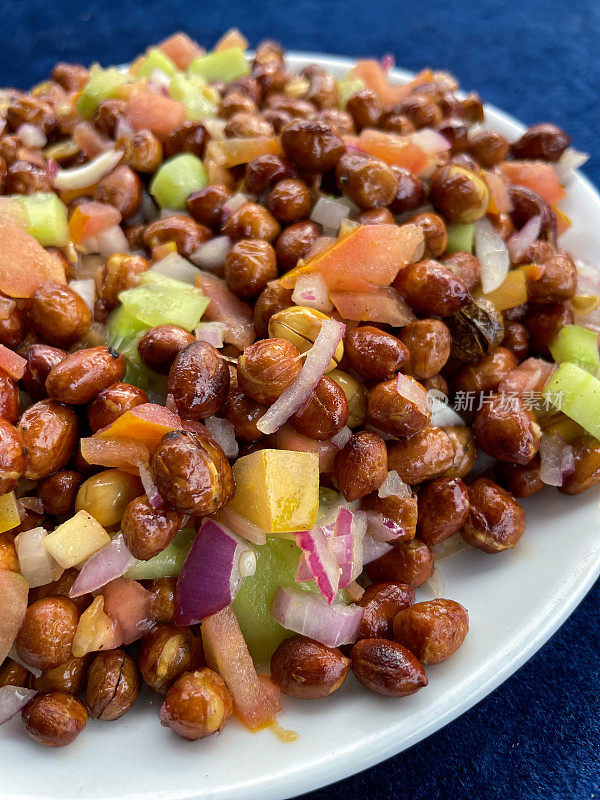 白色的碗里装着自制的花生masala chaat，街头风味小吃，花生，chaat masala，深蓝色天鹅绒背景，高视图，重点在前景